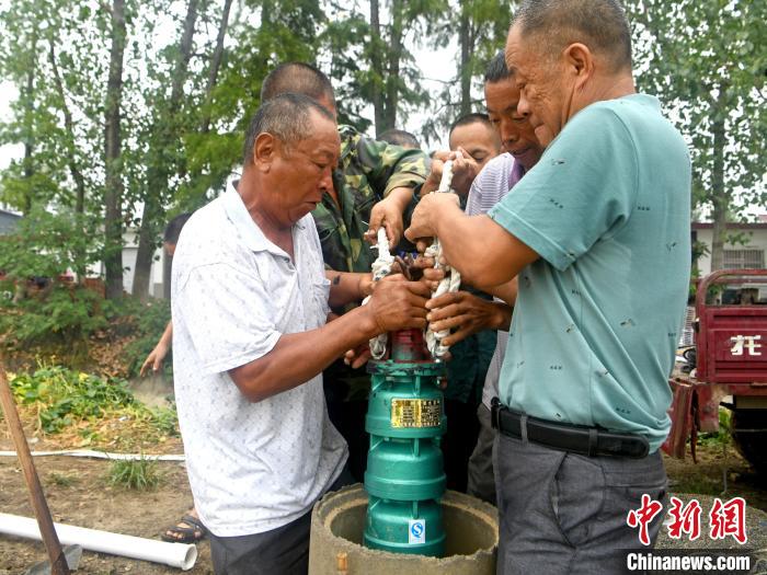淮南市寿县堰口镇魏岗村村民将新水泵放入刚打的井眼内,准备抽水灌溉.