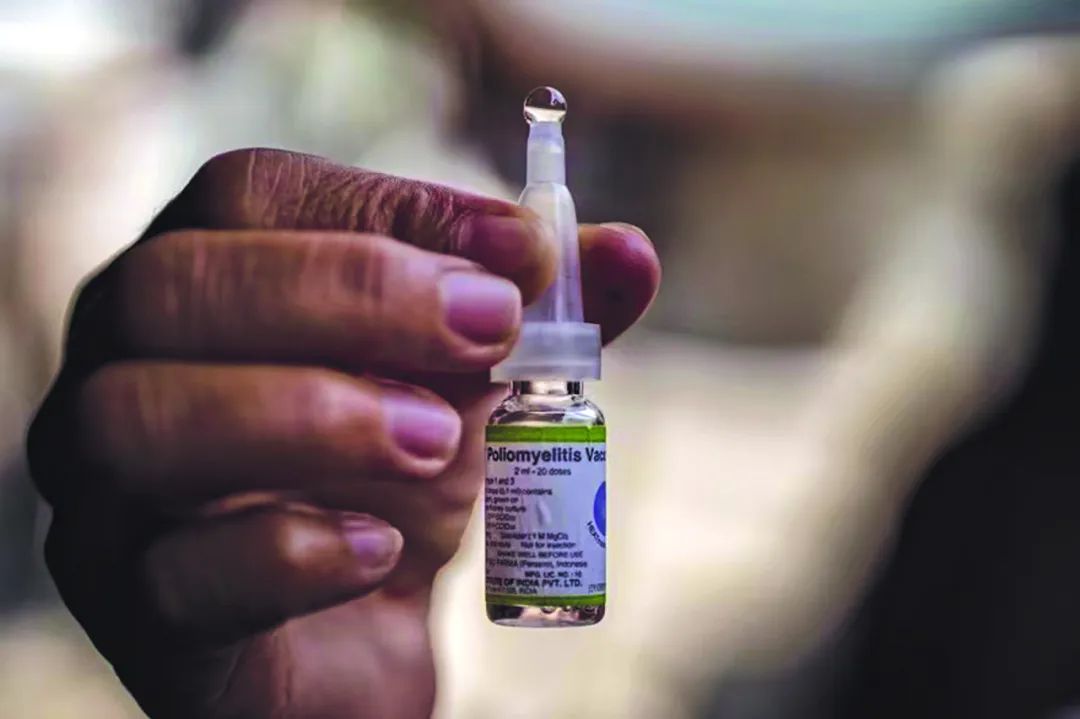 一名社区卫生工作者举起一小瓶口服脊髓灰质炎疫苗.