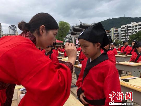 资料图:在“点朱启智”环节,先生在学童的额心点上朱砂,寓意孩子从此开启智慧,目明心亮。晓东 摄
