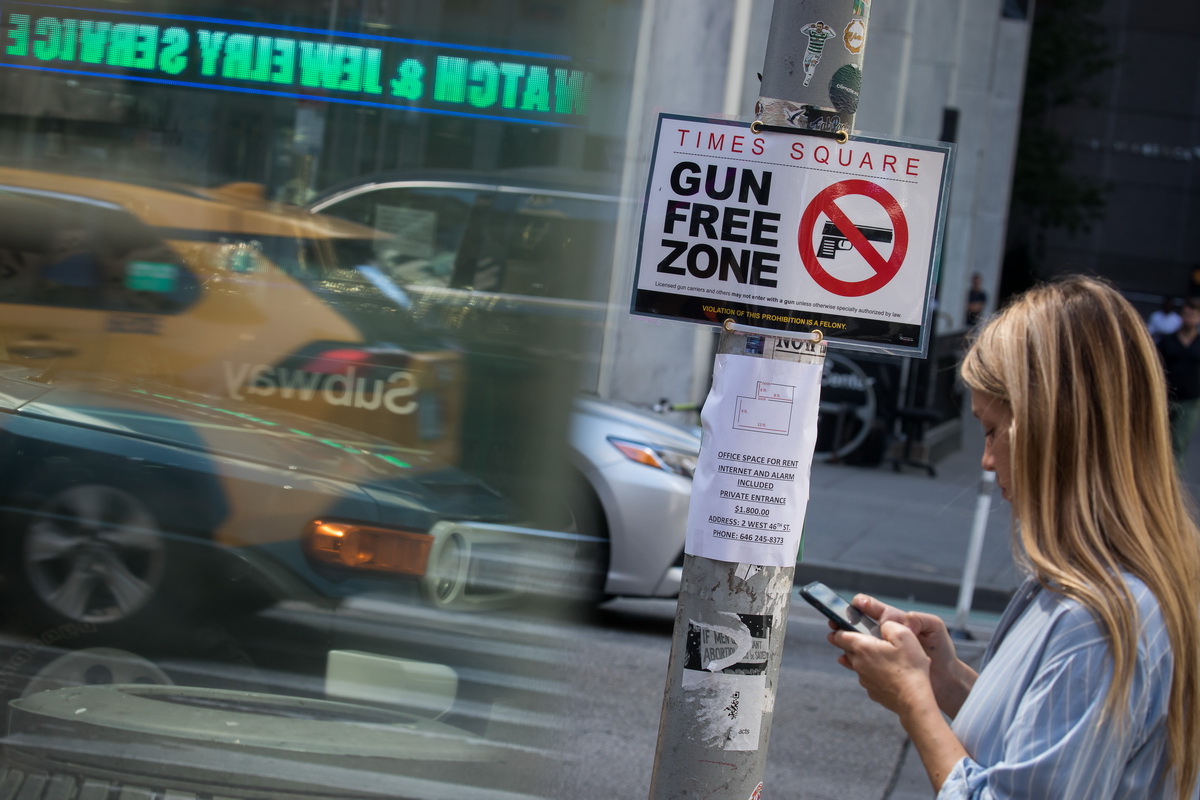 9月1日，人们从美国纽约时报广场支配街区的“禁枪区”标记牌旁走过。