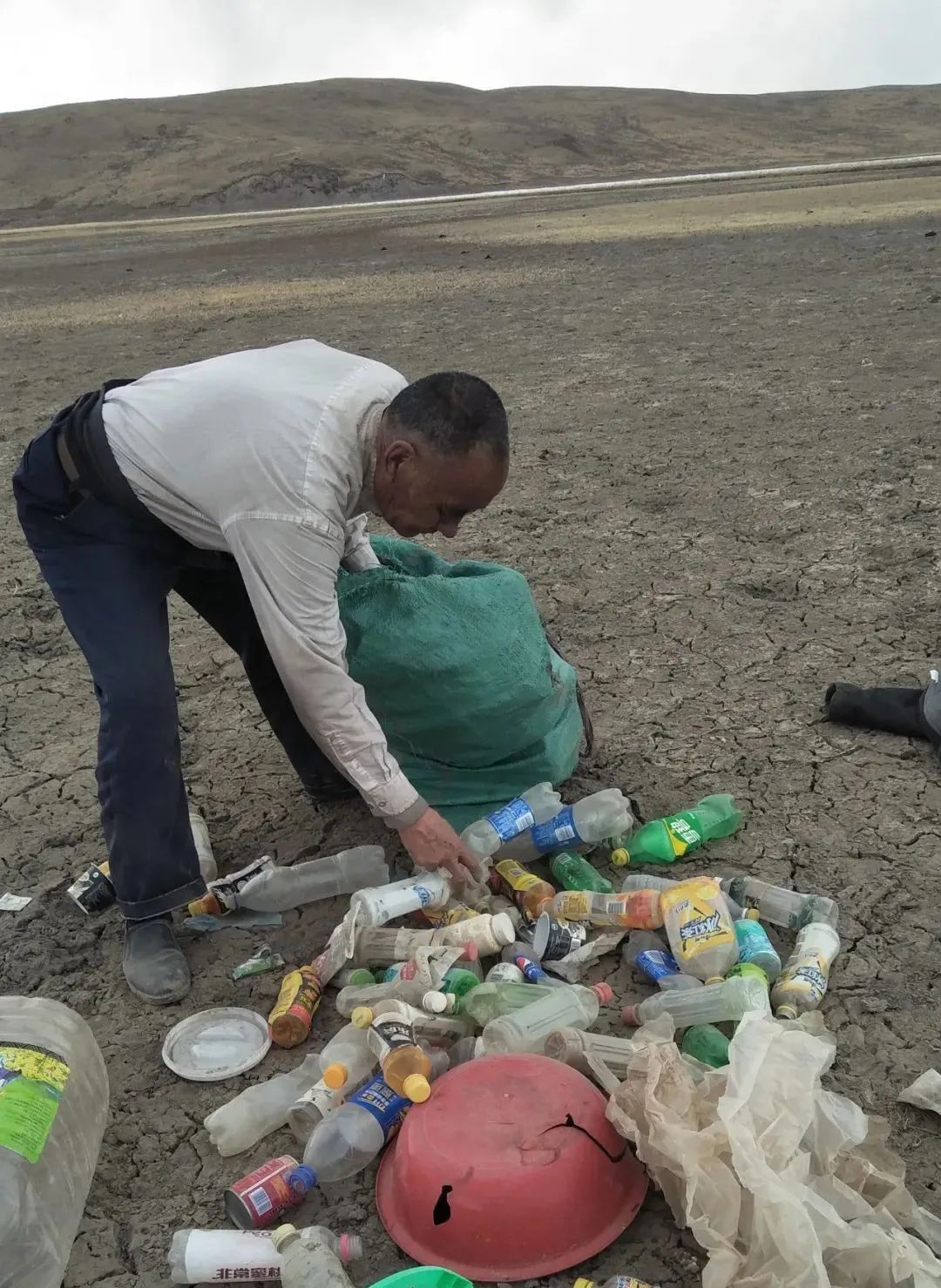 图为多杰老人在湿地内捡拾垃圾.图片来源:新华社