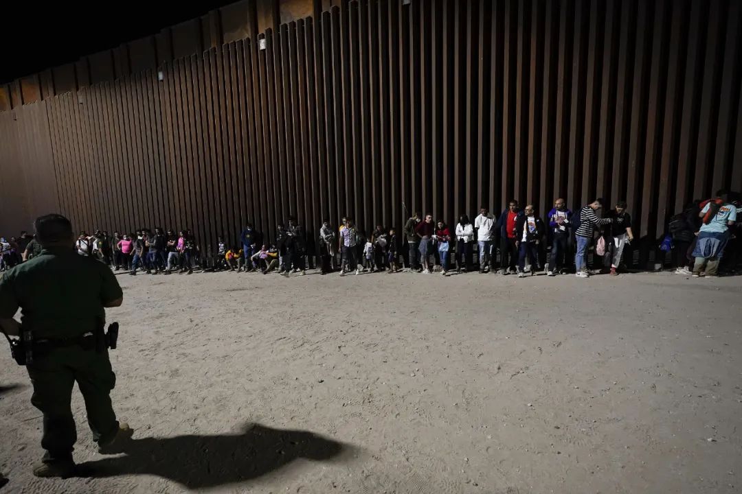 当地时辰8月23日，美国亚利桑那州尤马隔邻，外侨们在边境墙的至极恭候边境张望人员的搞定。图源：视觉中国
