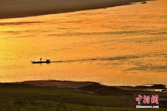 初秋时节黄昏时分打渔人划船在江中。石伟 摄