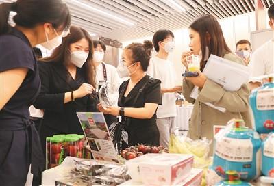 第五届进博会食品及农产品展区、医疗器械及医药保健展区展前供需对接会近日在国家会展中心（上海）举行。图为对接会嘉宾在参展企业展位前品尝水果。 新华社记者 方 喆摄