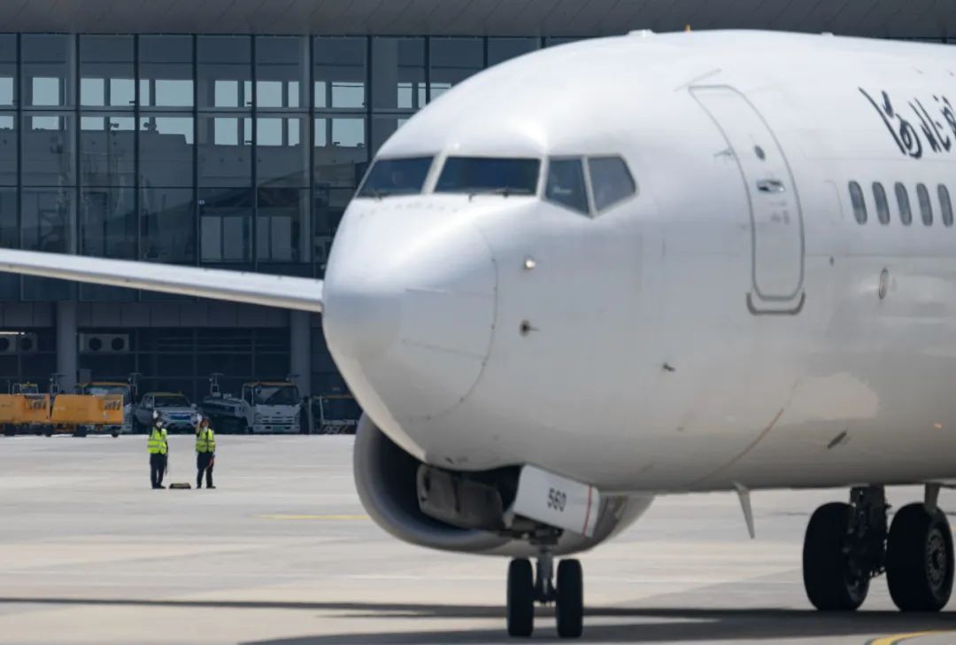 8月16日,北京大兴国际机场,两名机务人员正向放行的航班挥手告别.