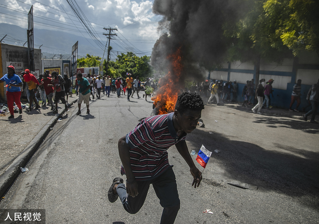 当地时间2022年10月17日，海地太子港，抗议者在抗议中走过燃烧的轮胎   图源：人民视觉
