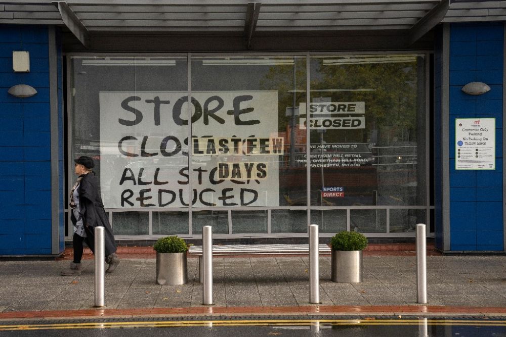 10月7日，在英国曼彻斯特，一名行人走过一家关闭的店铺。新华社发（乔恩·休珀摄）