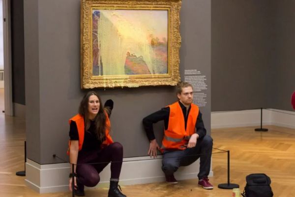 10月23日，在德国波茨坦一家博物馆，气候问题抗议者向莫奈名画《干草堆》泼洒豌豆汤，并把手粘在墙上。（美联社）