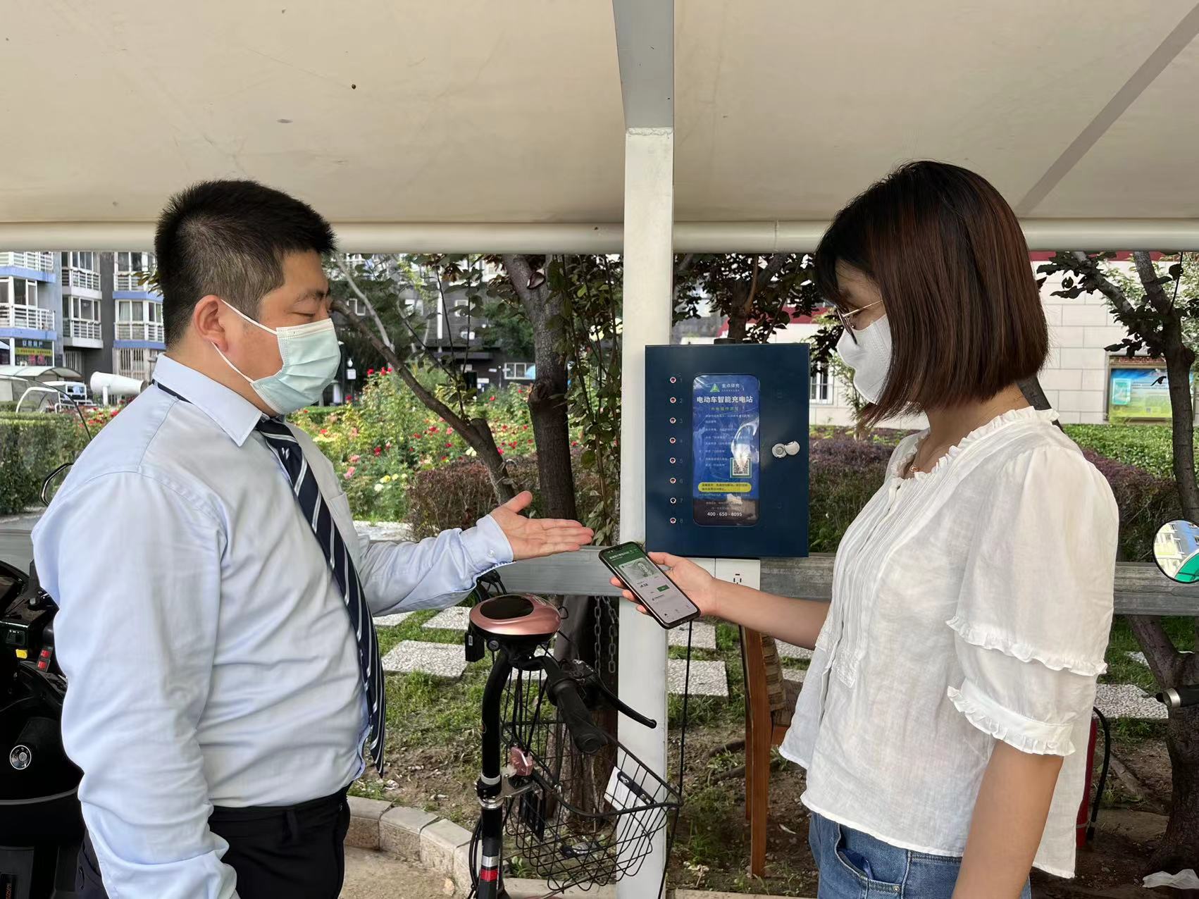 邮储银行朝阳区支行客户经理向社区居民介绍邮储银行数字人民币支付充电桩满减活动