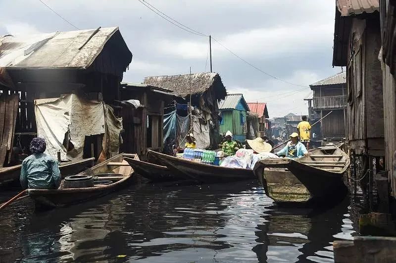 ▲当地时间2022年10月19日，尼日利亚拉各斯，人们在贫民窟里用平底船运送货物。图/视觉中国