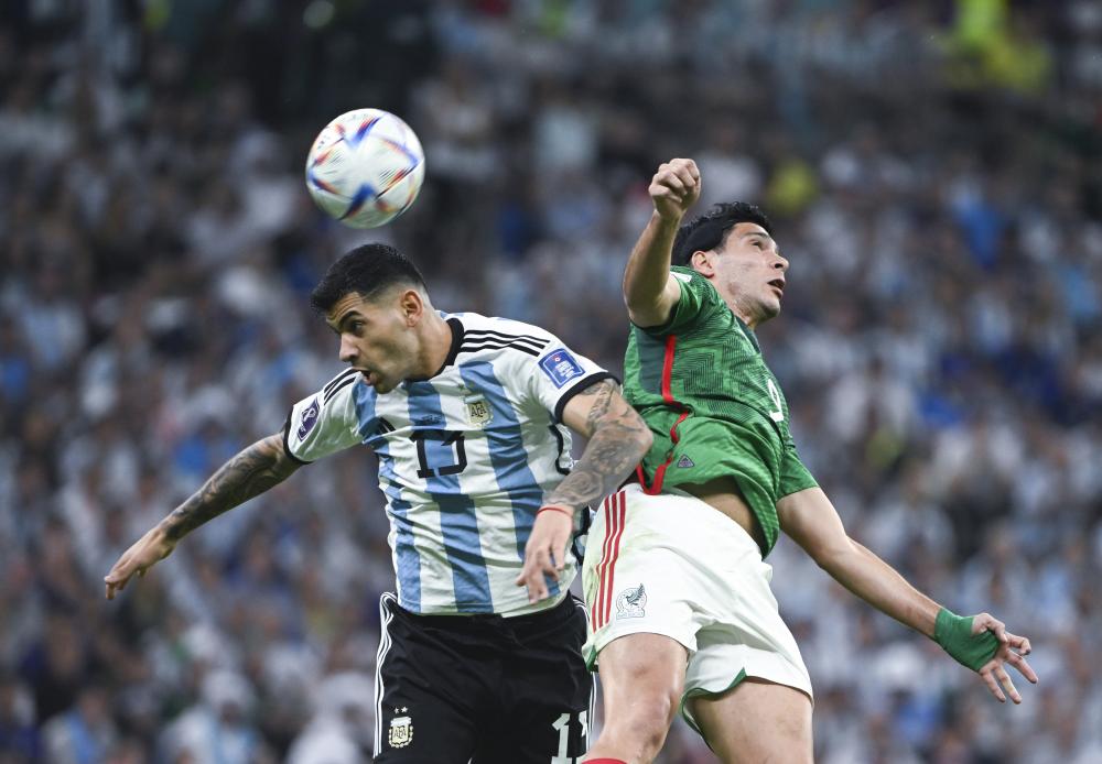 11月26日，阿根廷队球员克·罗梅罗（左）和墨西哥队球员劳尔·希门尼斯在比赛中争顶。 新华社记者 李尕 摄
