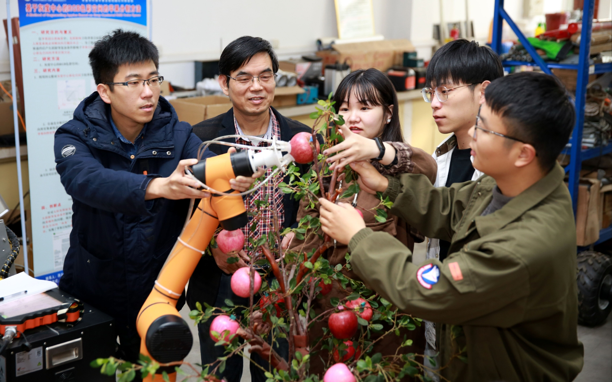 杨福增教授（左二）和团队成员在探讨机器人手臂抓取苹果的技巧。受访者供图
