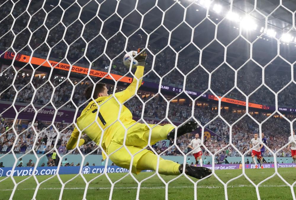 11月30日,波兰队守门员什琴斯尼在比赛中扑出阿根廷队球员梅西的点球.