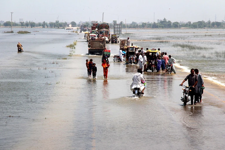 8月，人们穿过巴基斯坦信德省被洪水淹没的高速公路。