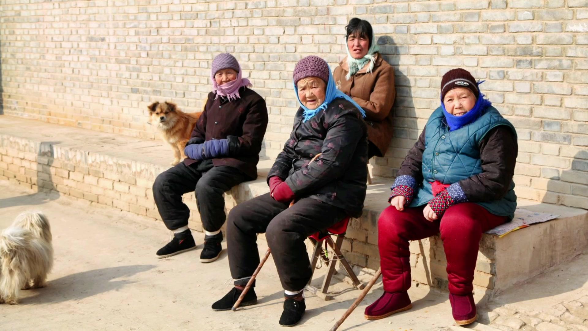 墙根下晒太阳的老人