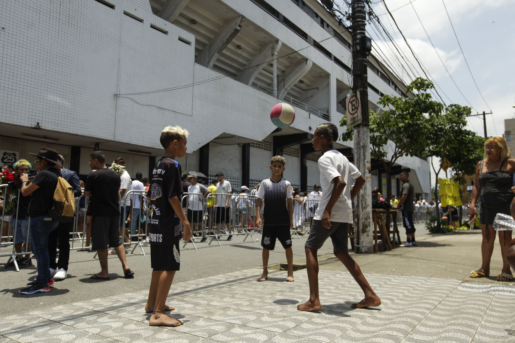2023年1月2日，巴西桑托斯，大批民众排队向贝利告别，孩子们在队伍前踢足球。