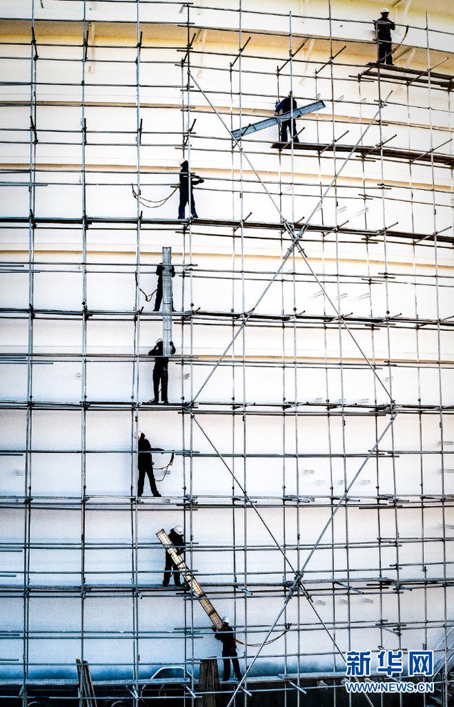 　　2023年1月1日，在建筑施工脚手架上，施工人员在传递着施工材料。新华网发 （刘武基 摄）