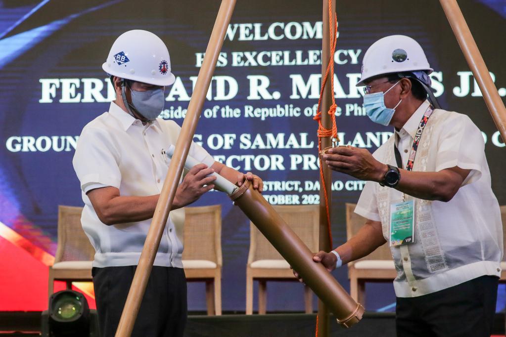 10月27日，在菲律宾达沃，菲律宾总统马科斯（左）与菲律宾公共工程和公路部长曼努埃尔·博诺安在达沃-萨马尔大桥的开工仪式上埋设时间胶囊。