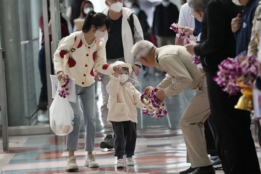 当地时间2023年1月9日,泰国曼谷,泰国官员向抵达素万那普国际机场的中国游客发放花环。