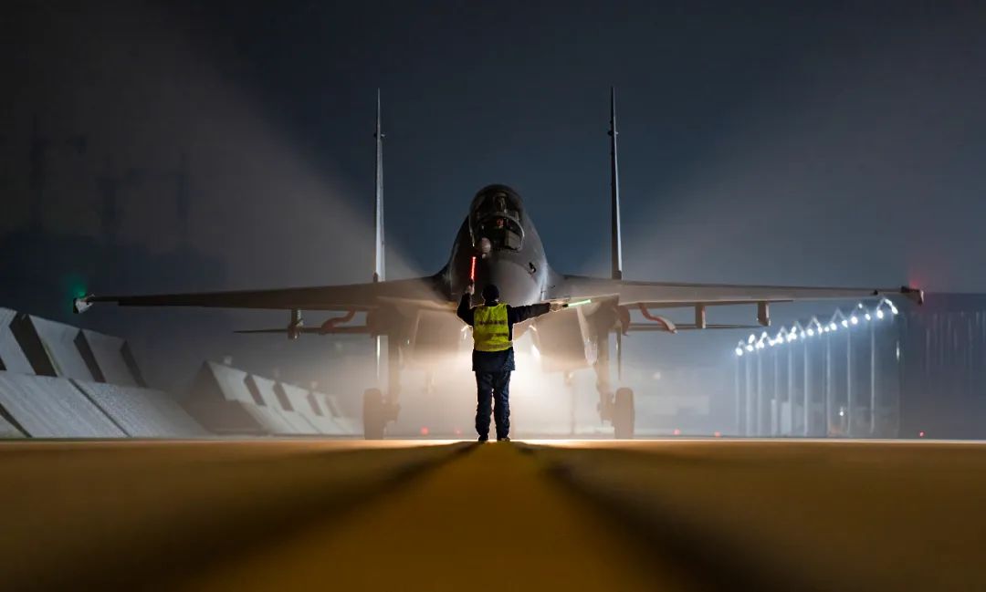 机务人员指挥战机停入机位.