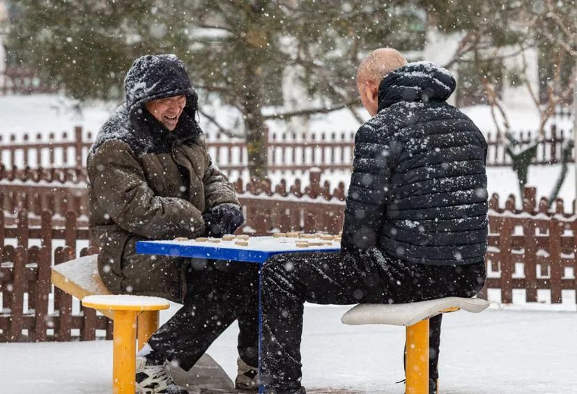 2022年2月13日,北京,两位老人在雪中下棋.(段旭升 摄)