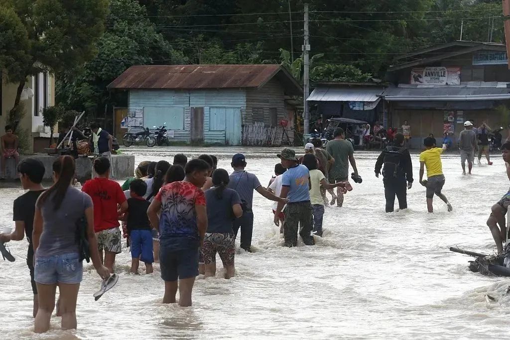 ▲当地时间2022年11月17日，菲律宾达沃，暴雨引发山洪暴发，居民穿过被洪水淹没的道路。图/视觉中国