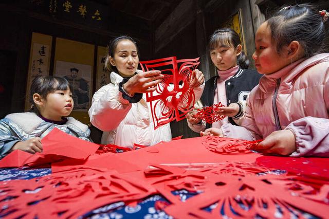1月12日,安徽省宁国市胡乐镇古镇宅院里,当地的剪纸非遗传承人教孩子
