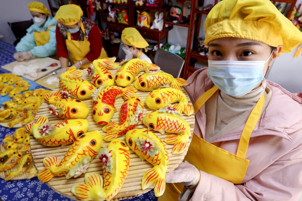 1月13日,山东省枣庄市龙山路街道居民在展示制作的传统"面鱼".
