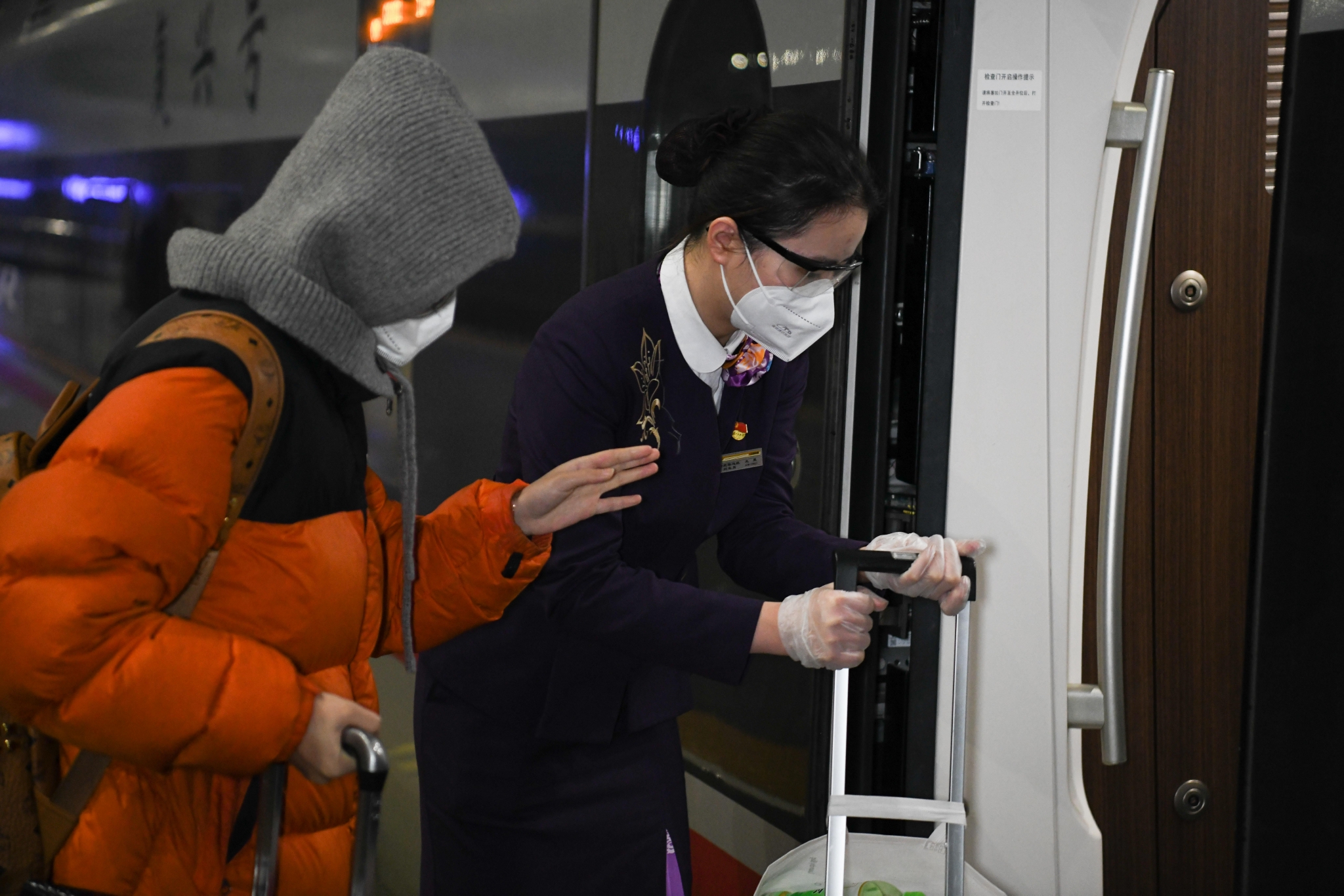 中国铁路上海局集团有限公司合肥客运段列车员王昊(右)引导旅客上车