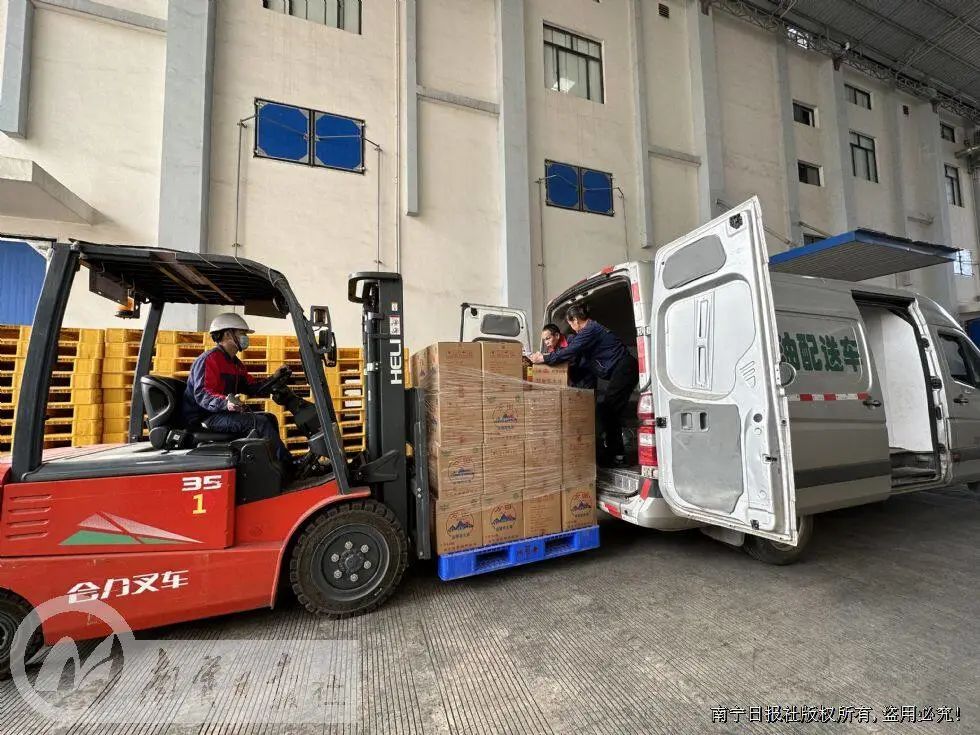 军粮供应站工作人员驾驶叉车将成品花生油装上粮油配送车.