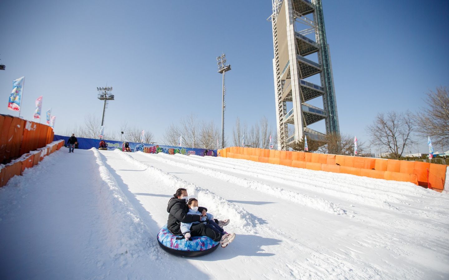 第十二届鸟巢欢乐冰雪季开幕,家长带着小朋友从坡道滑下.