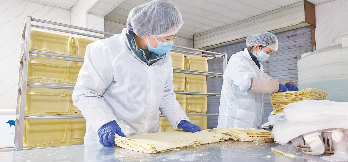 大堡子镇浩阳豆制品加工部,半自动化生产线上的工人在忙碌着.