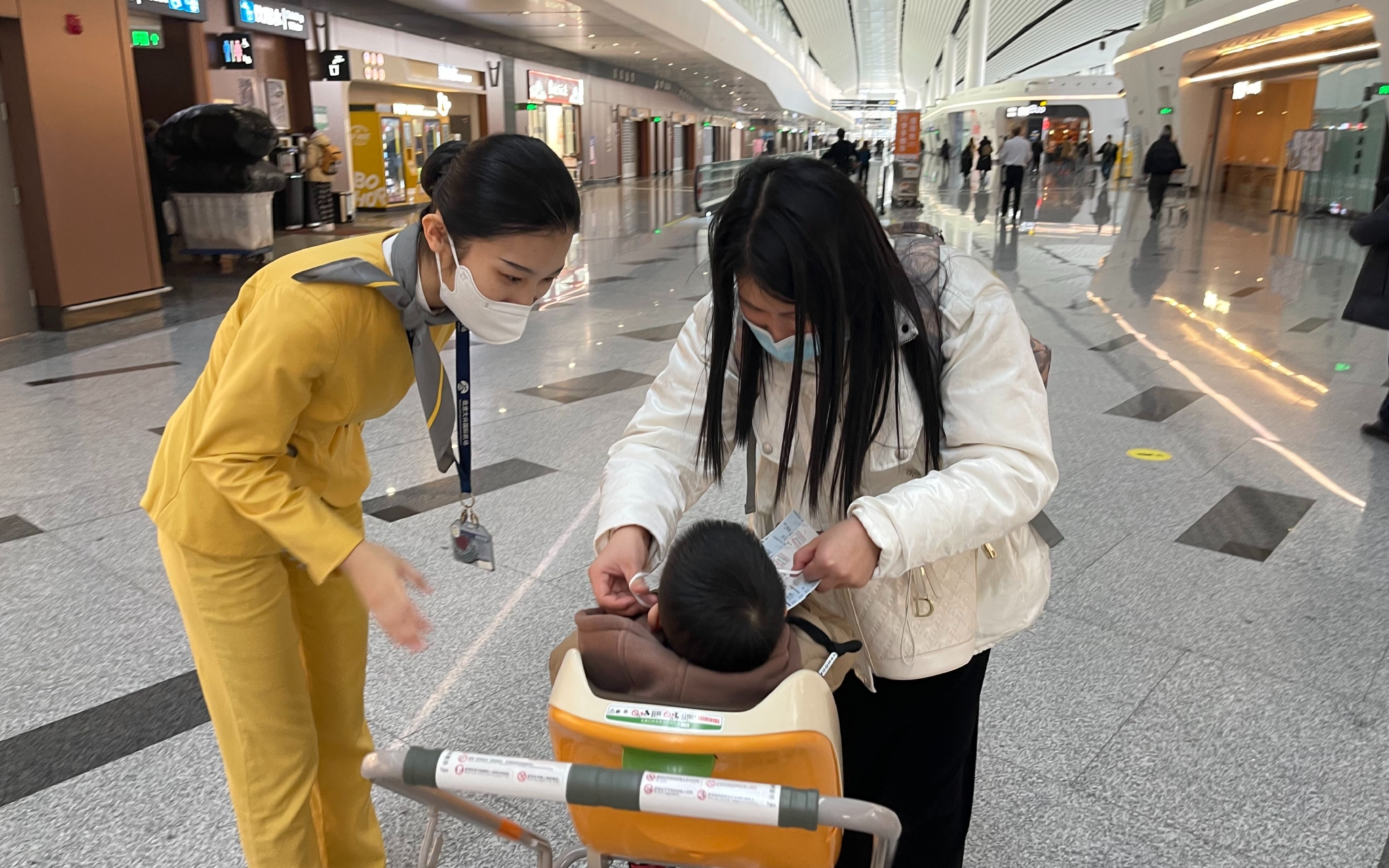 大兴机场指廊管家王海雅提醒旅客帮小朋友戴好口罩。新京报记者 吴婷婷 摄