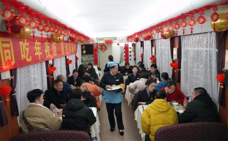 T95次列车上,旅客和工作人员一起吃年夜饭。(中国铁路武汉局集团有限公司武汉客运段供图)