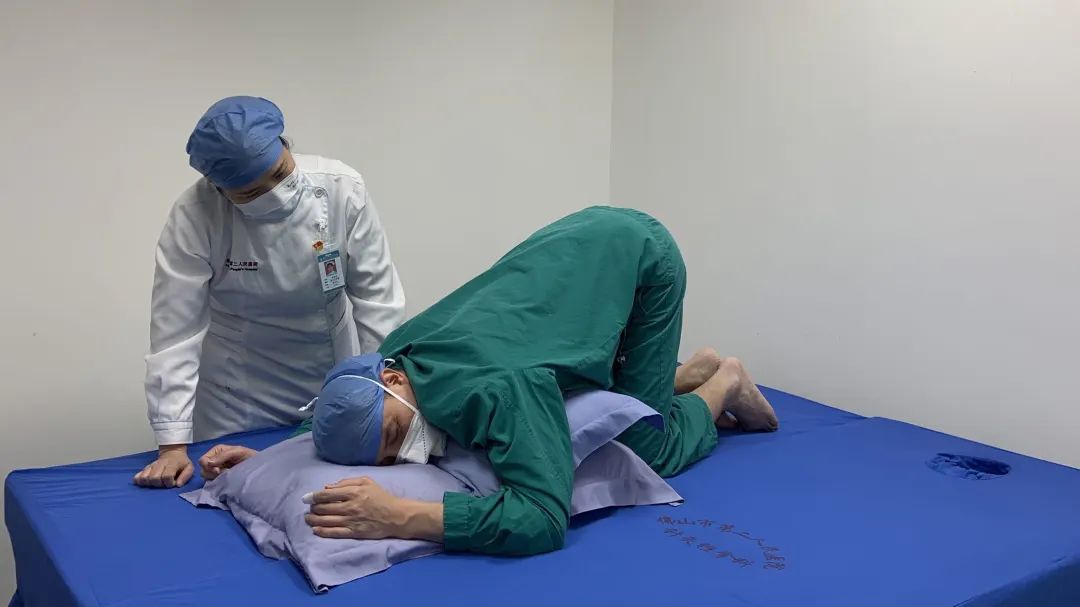 吴医生在进行俯卧位(胸膝卧位)通气治疗动作解说.