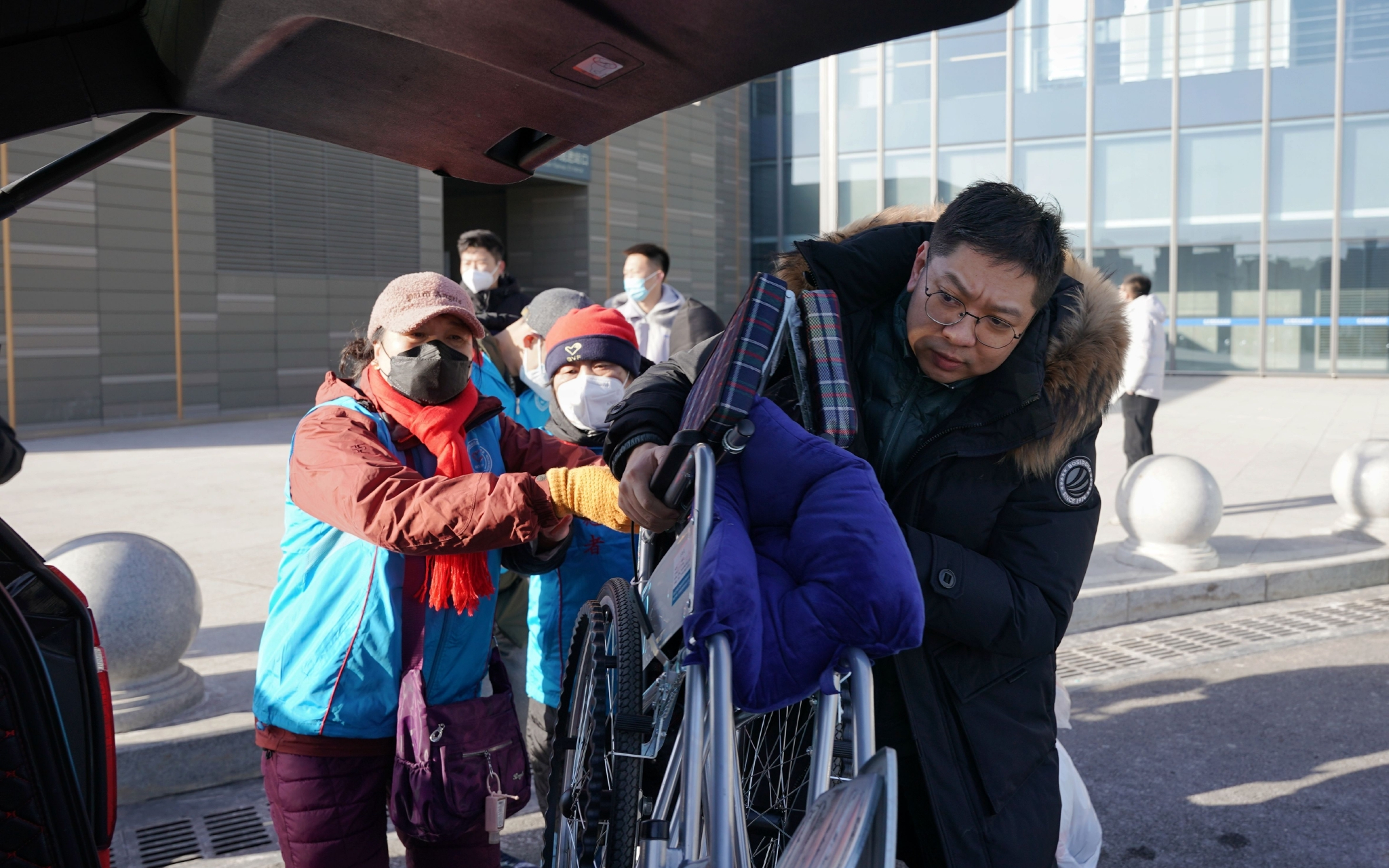 爱心司机与志愿者一起帮助旅客搬运轮椅。新京报记者 王贵彬 摄