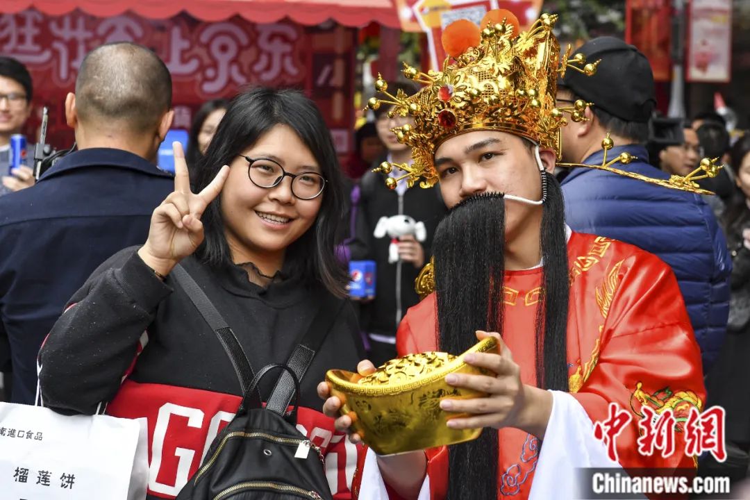 2019年2月，市民在广州西湖花市上与“财神”合影留念。陈骥旻 摄