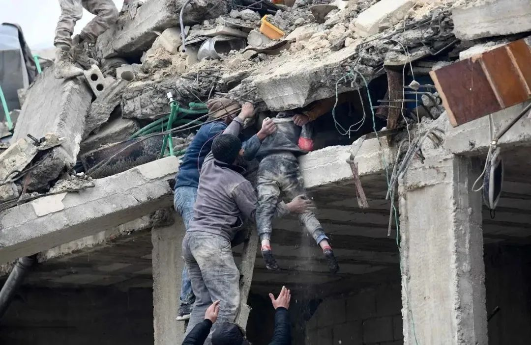 叙利亚阿勒颇，居民们从地震后倒塌的建筑物废墟中救出一名受伤的女孩