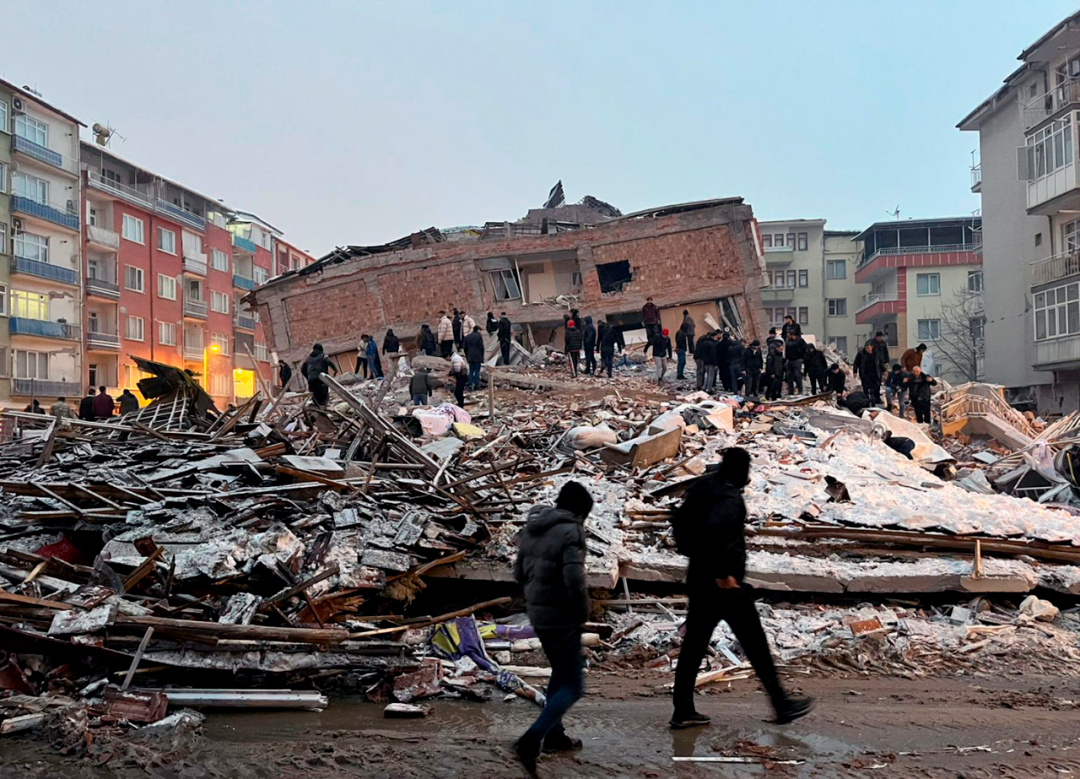2月6日，人们聚集在土耳其马拉蒂亚一处倒塌的建筑附近。图源：新华社发，穆斯塔法·卡亚 摄