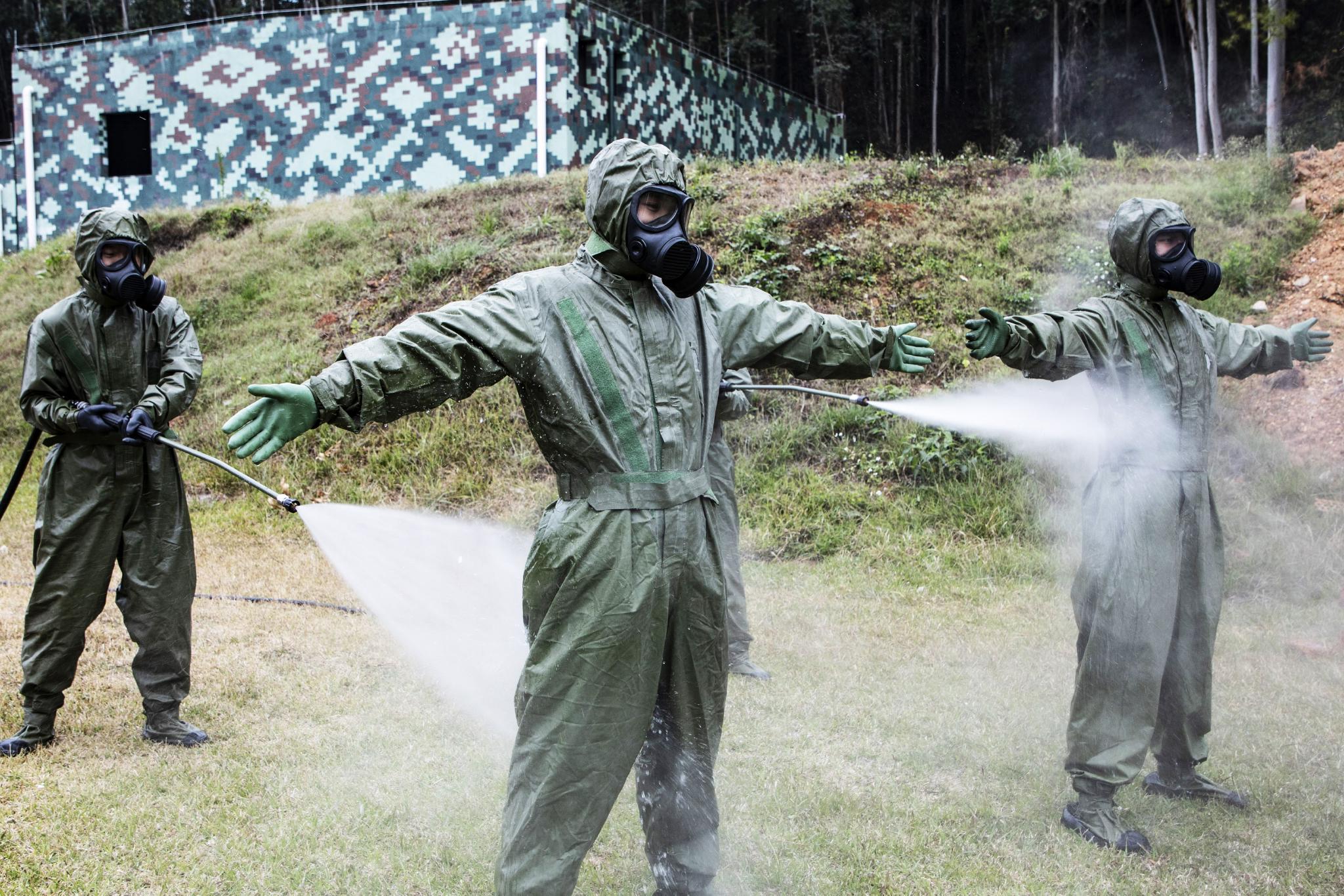 防化分队官兵正在对进入染毒区内人员进行清洗消毒.
