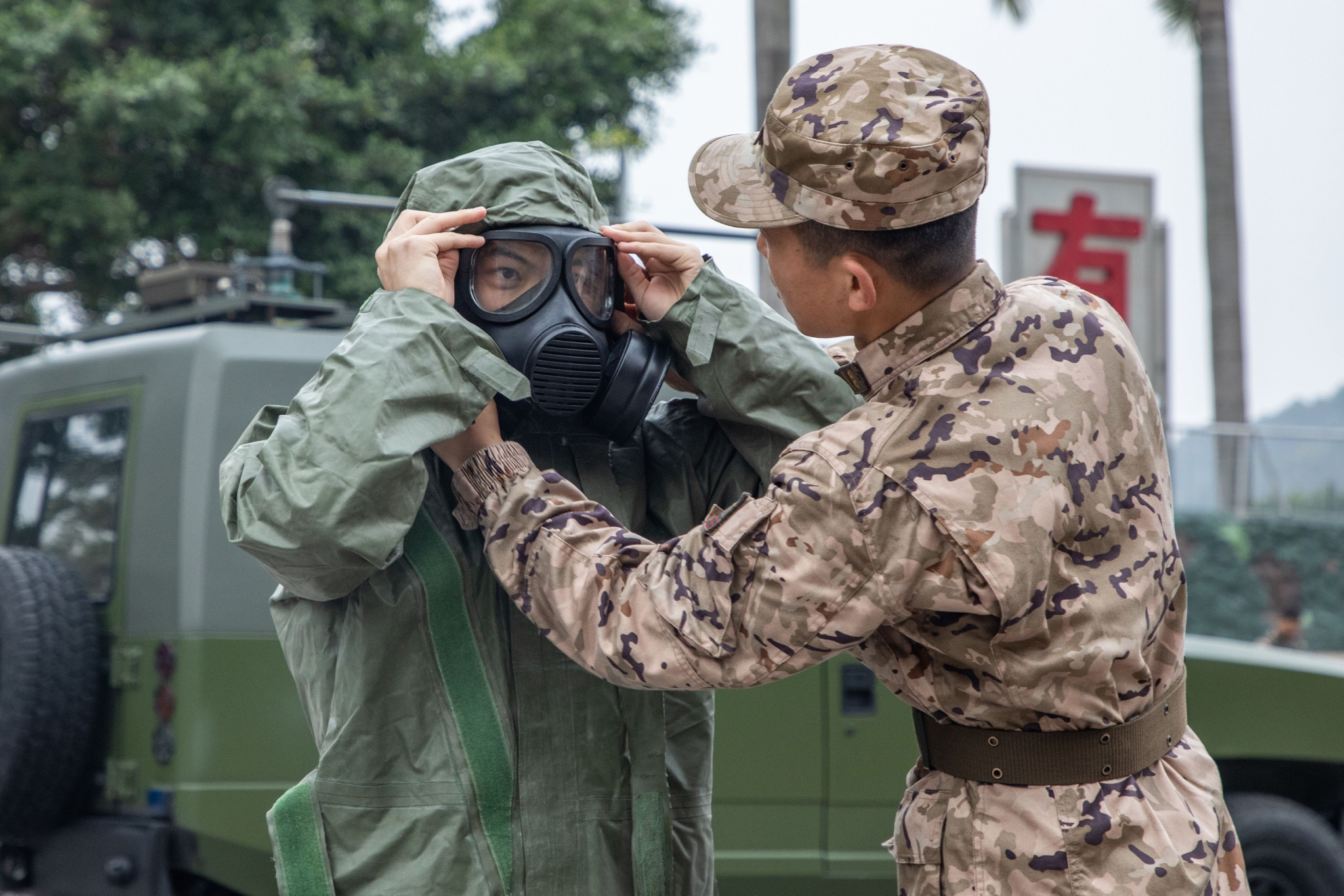 防化分队官兵协作穿戴防护服.