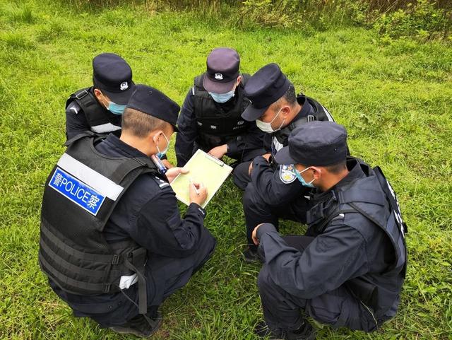图为移民管理警察在山林间研究抓捕方案.