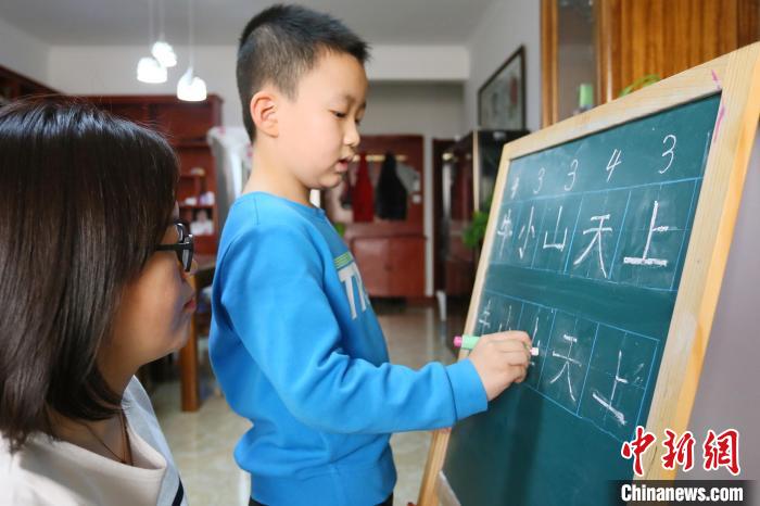 资料图：甘肃兰州市七里河区王家堡小学学生芮明亮在家给家长讲解汉字笔画，这也是他的寒假作业之一。艾庆龙 摄