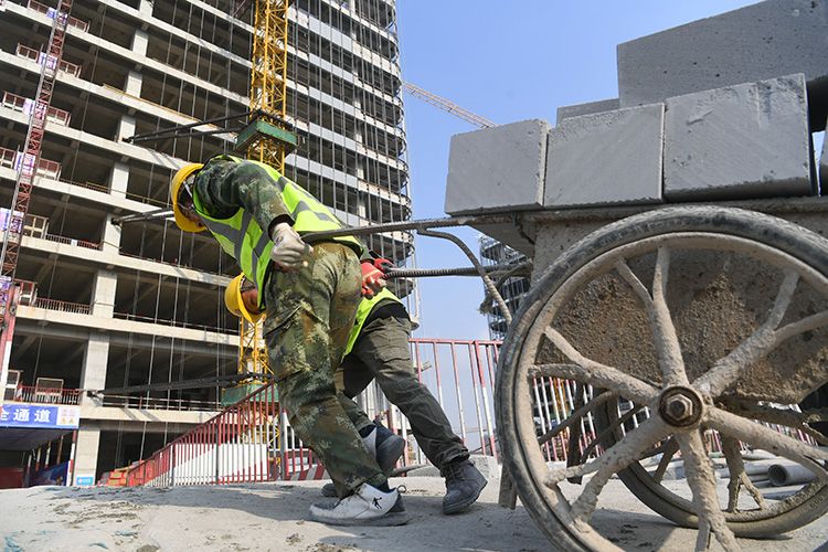 正在施工的楼宇建筑之间,运送着砌筑墙体所用的材料,水泥泵车不时轰鸣