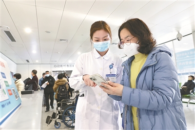 江苏省人民医院门诊部护士指导患者使用手机自助挂号。