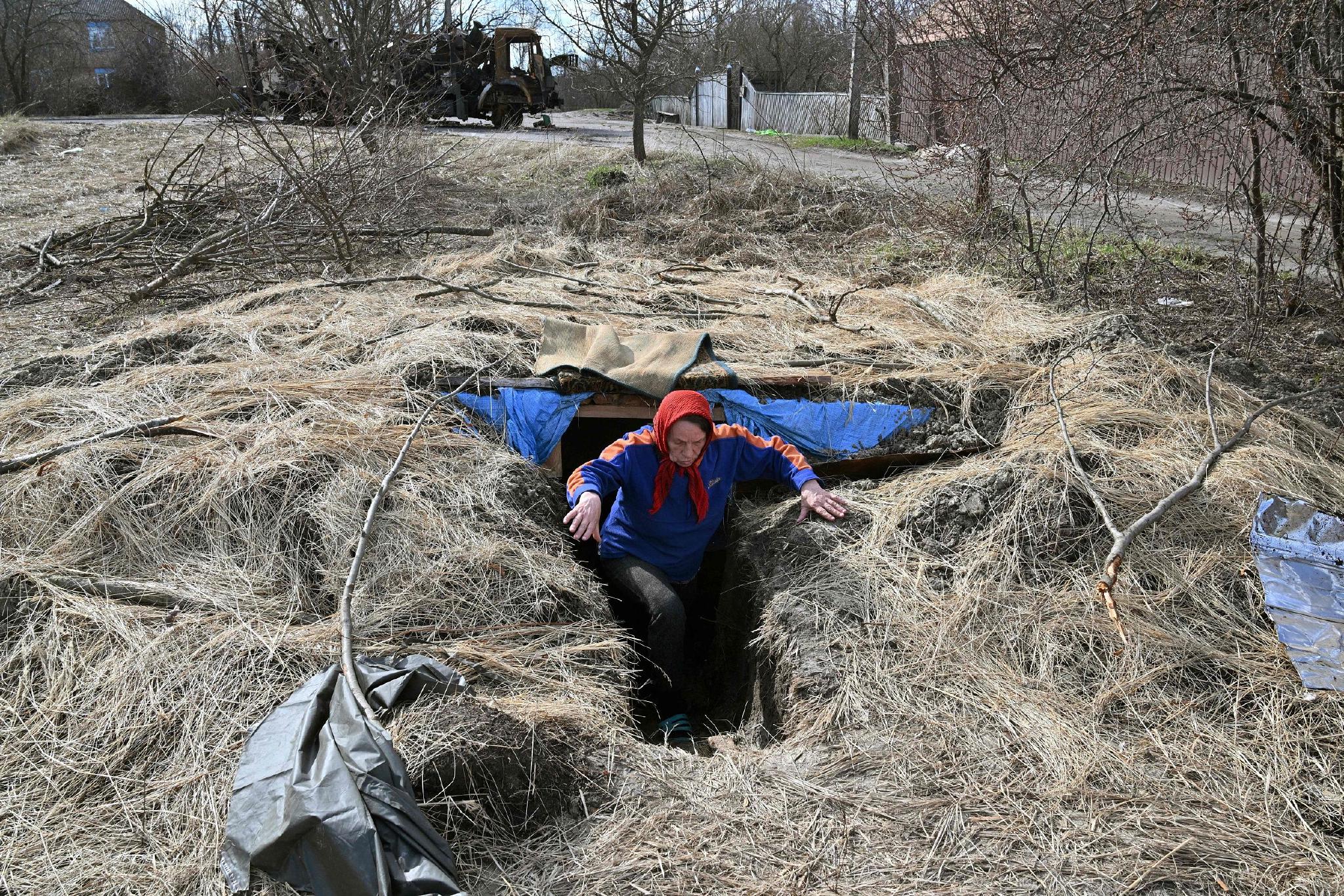 当地时间2022年4月7日，乌克兰北部城市Obukhovychi，当地一位老妇从俄罗斯士兵的战壕中出来。   视觉中国 图