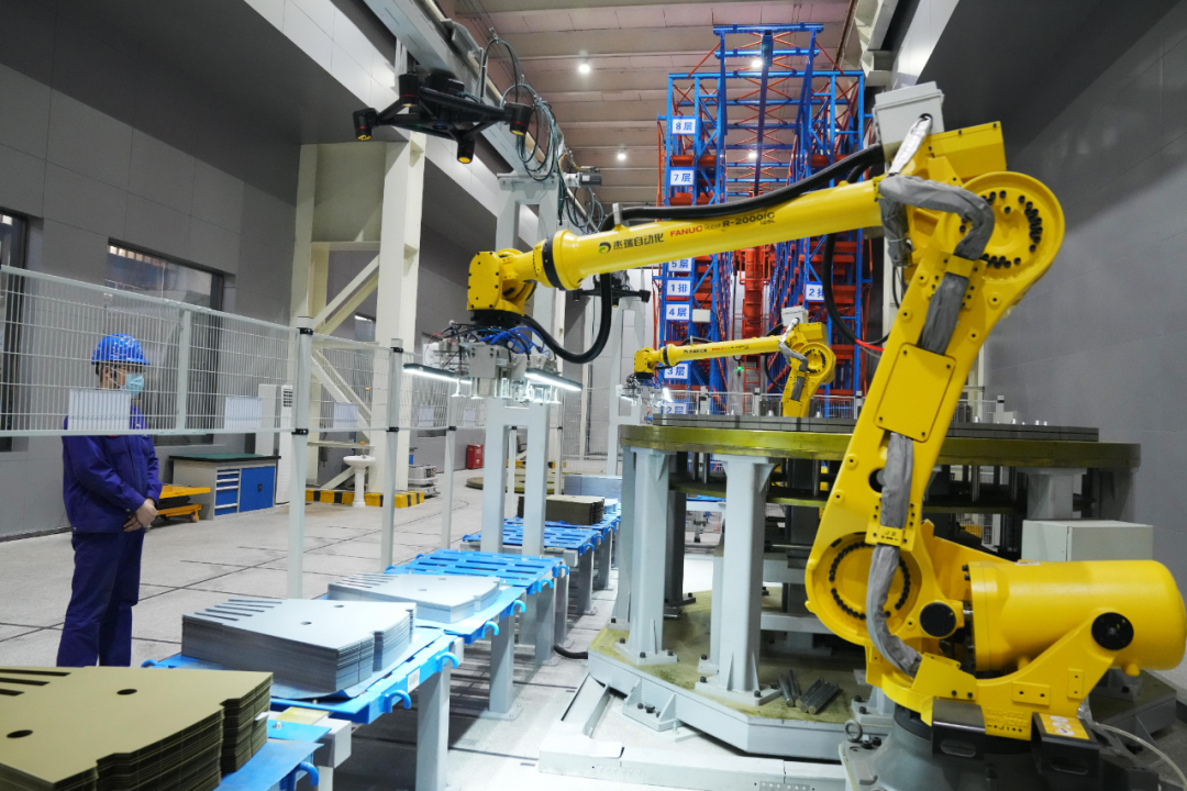 哈尔滨电机厂有限责任公司的数字化智能示范车间,工人观察机械臂作业