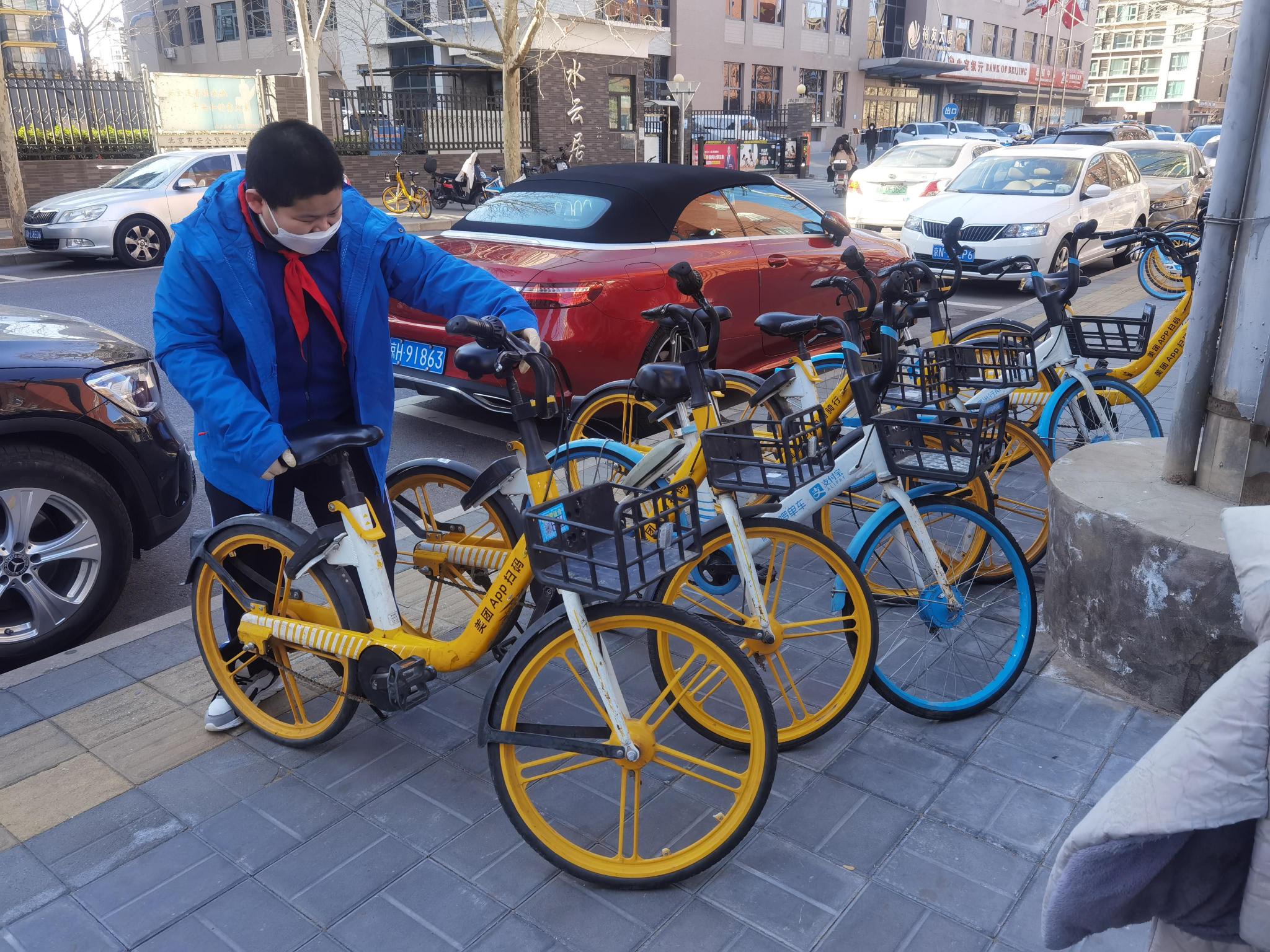 北京市盲人学校学生将路边的共享单车摆放整齐.学校供图