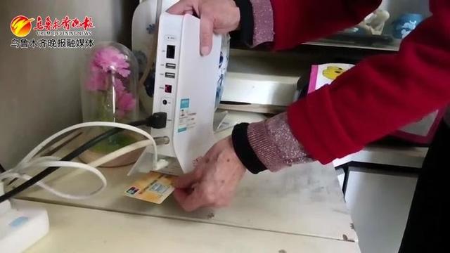 图为:市民正在家中正将燃气ic卡插入"天山云tv"机顶盒,准备购气.