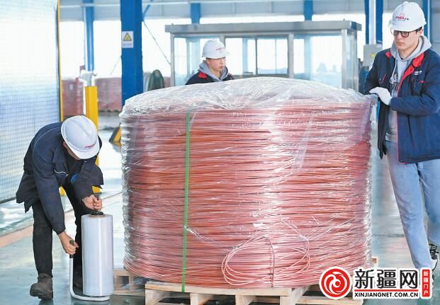 在正威新疆新材料產業園連鑄連軋設備車間成品包裝區，操作人員正在對成品銅線杆進行包裝作業。 （全媒體記者陳巖攝）